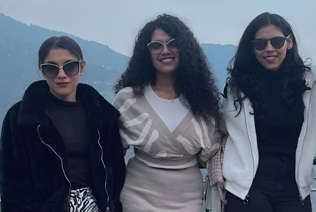 Three women posing outdoors with a mountainous background