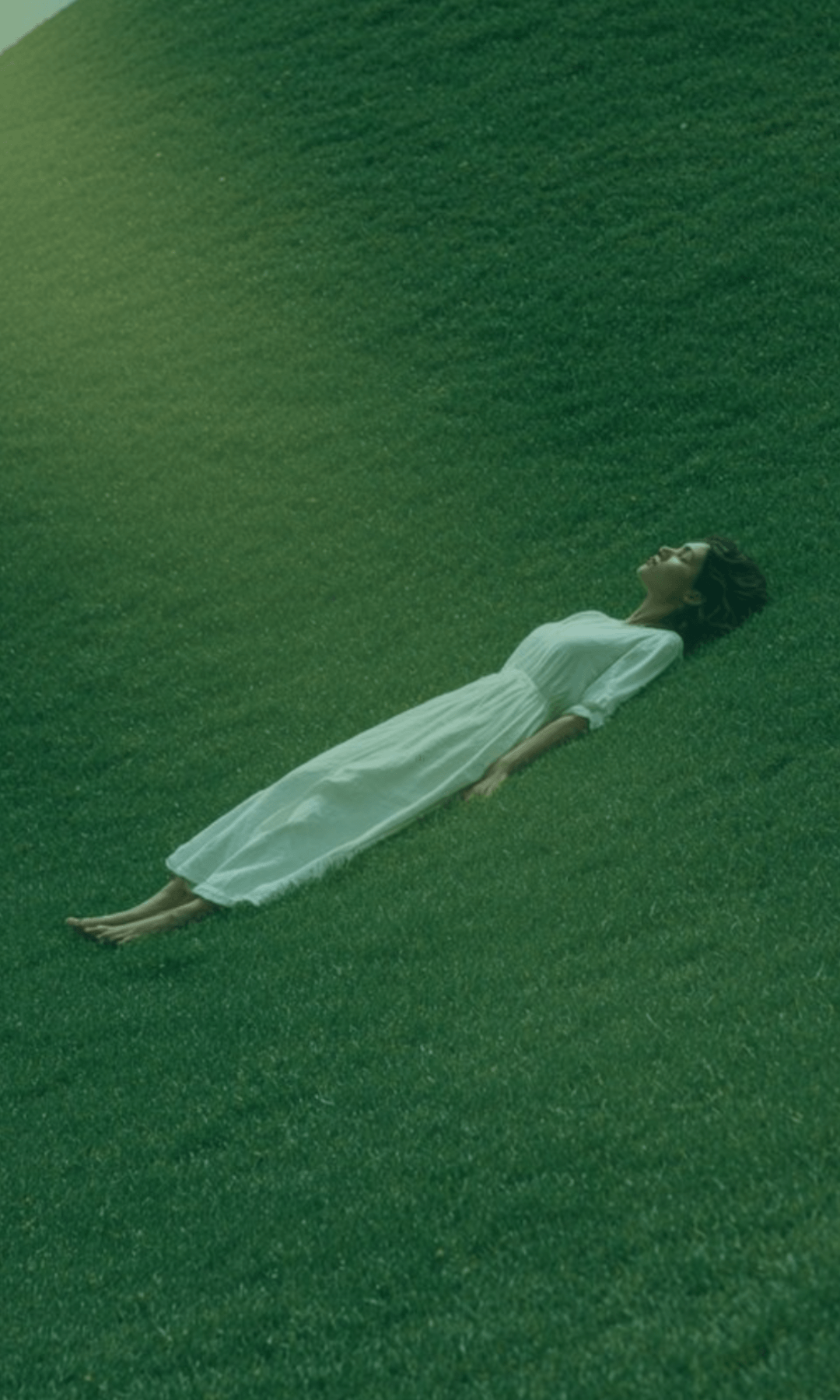 Person lying on a grassy field with a gradient green filter